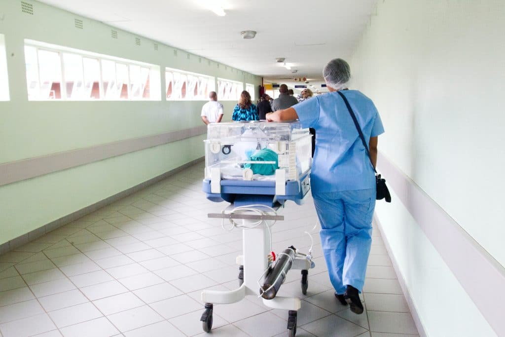 Nurse moving baby's hospital bed